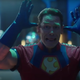 John Cena, in his Peacemaker outfit, puts his thumbs to his wars and wiggles his fingers at the camera.